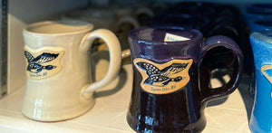 Colorful coffee mugs in Squam Market that say Squam Lake, NH